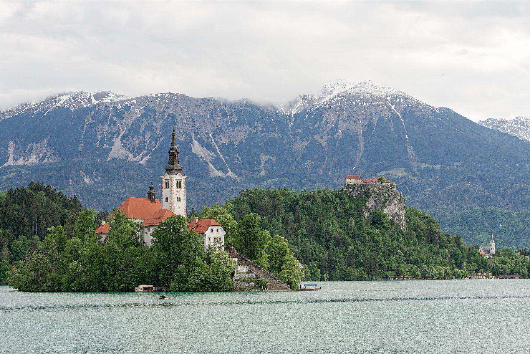 Bled Island and its pilgrimage church floating on Lake Bled, with the clifftop castle behind